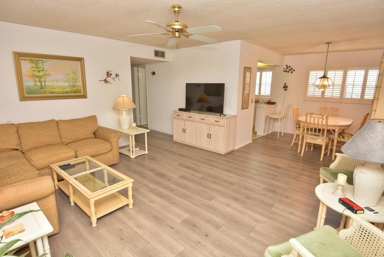 A living room and dining area feature light wood-look flooring, a ceiling fan, and furniture — 1225 NW 21st Street # 3506, Stuart FL 34994, STUART, FL