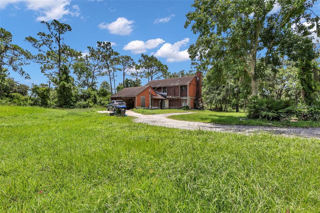 A two-story house with wood siding and an attached garage sits on a grassy lot — 24003 SISLER AVENUE, CHRISTMAS, FL