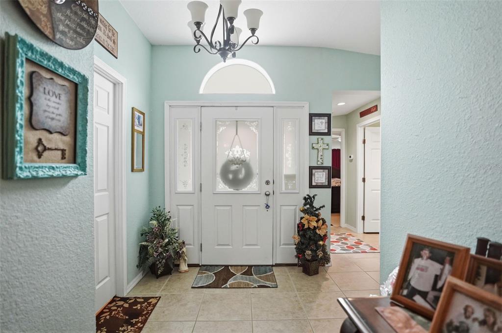 A bright entryway features light blue walls, tile flooring, a chandelier, and a white front door — 14358 MIDFIELD STREET, BROOKSVILLE, FL