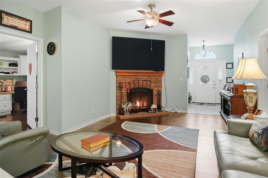 A living room features a stone fireplace, a wall-mounted television, and a ceiling fan — 14358 MIDFIELD STREET, BROOKSVILLE, FL