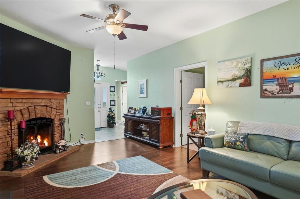 A living room features a stone fireplace, hardwood floors, a ceiling fan, and a sofa — 14358 MIDFIELD STREET, BROOKSVILLE, FL