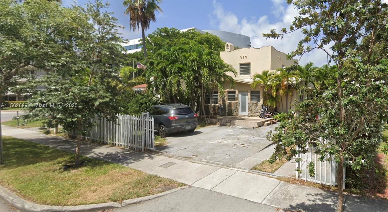 A two-story house with a concrete driveway, white fence, and palm trees in the yard — 1710 Jefferson Ave, Miami Beach FL 33139, MIAMI BEACH, FL
