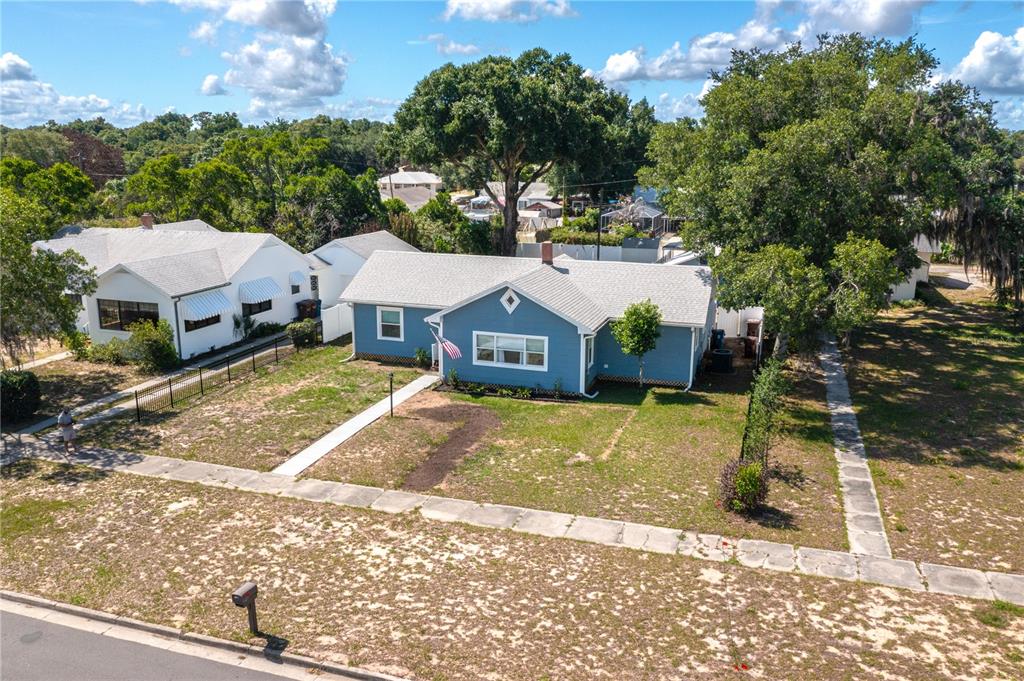 An aerial view shows a blue single-story house with a white roof and lawn — 414 E BULLARD AVENUE, LAKE WALES, FL