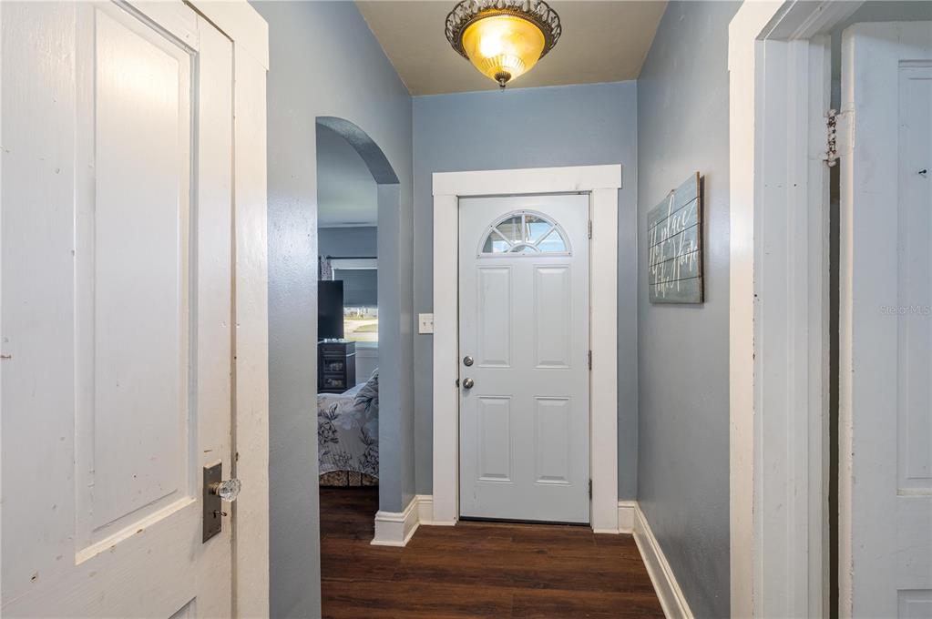 A hallway with blue walls, wood-look flooring, a white front door, and an arched entryway — 414 E BULLARD AVENUE, LAKE WALES, FL