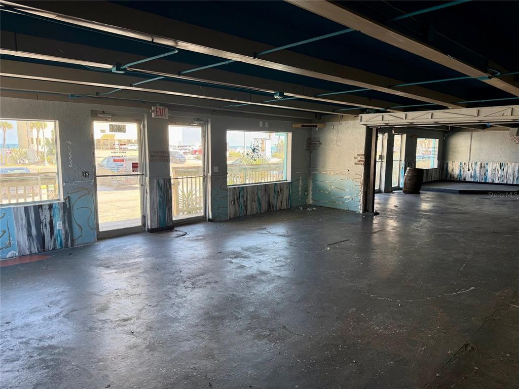 An empty commercial space features concrete floors, exposed ceiling beams, and large windows facing outdoors — 3400 S ATLANTIC AVENUE UNIT 3400 & 3404, DAYTONA BEACH, FL