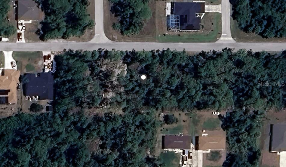 This aerial view shows a wooded residential lot situated between existing houses and a road — 18289 POSTON AVENUE, PORT CHARLOTTE, FL