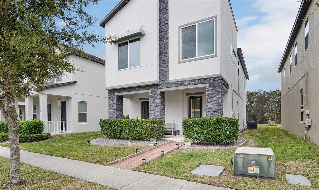 A two-story house features white stucco siding, stone accents, and a brick walkway — 9972 PALLIDA HICKORY WAY, WINTER GARDEN, FL