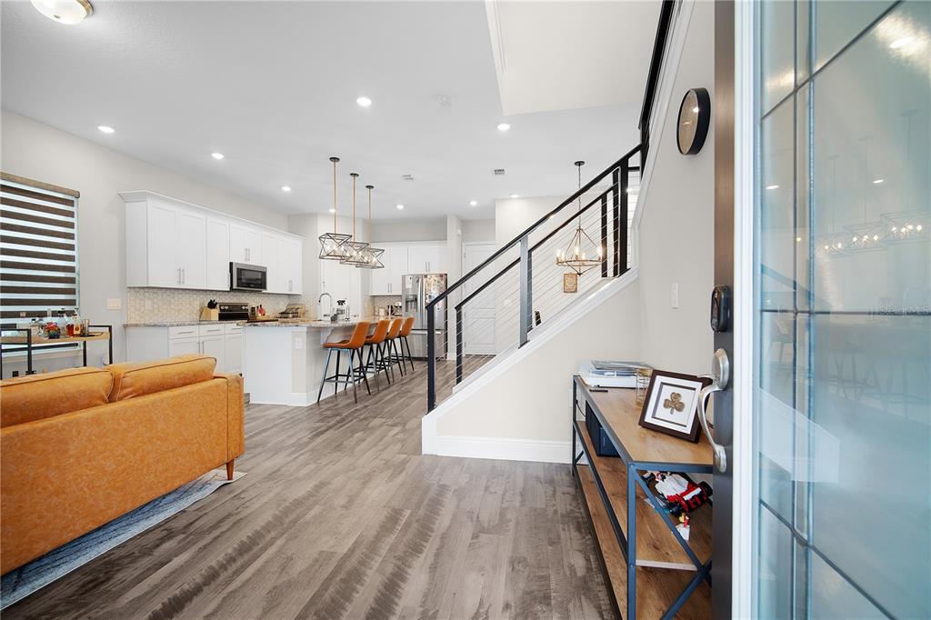 An open-concept kitchen and living area featuring white cabinets, a kitchen island, and wood flooring — 9972 PALLIDA HICKORY WAY, WINTER GARDEN, FL