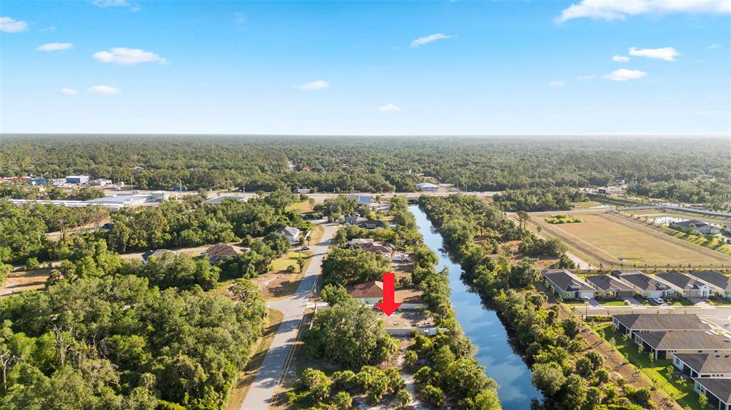 An aerial view shows a vacant lot marked by a red arrow beside a canal — 764 BOWMAN TERRACE, PORT CHARLOTTE, FL