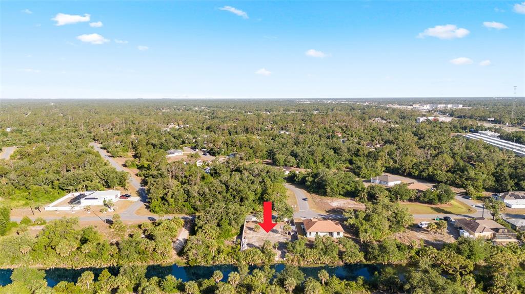 An aerial view shows a vacant residential lot marked by a red arrow near water — 764 BOWMAN TERRACE, PORT CHARLOTTE, FL