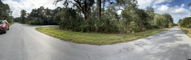 A panoramic view of a corner lot featuring a paved road intersection and wooded vegetation — 12564 E WELON AVENUE, PORT CHARLOTTE, FL