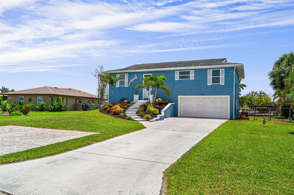 A two-story blue house features a white garage door, front stairs, and a concrete driveway — 5404 BAY STATE ROAD, PALMETTO, FL