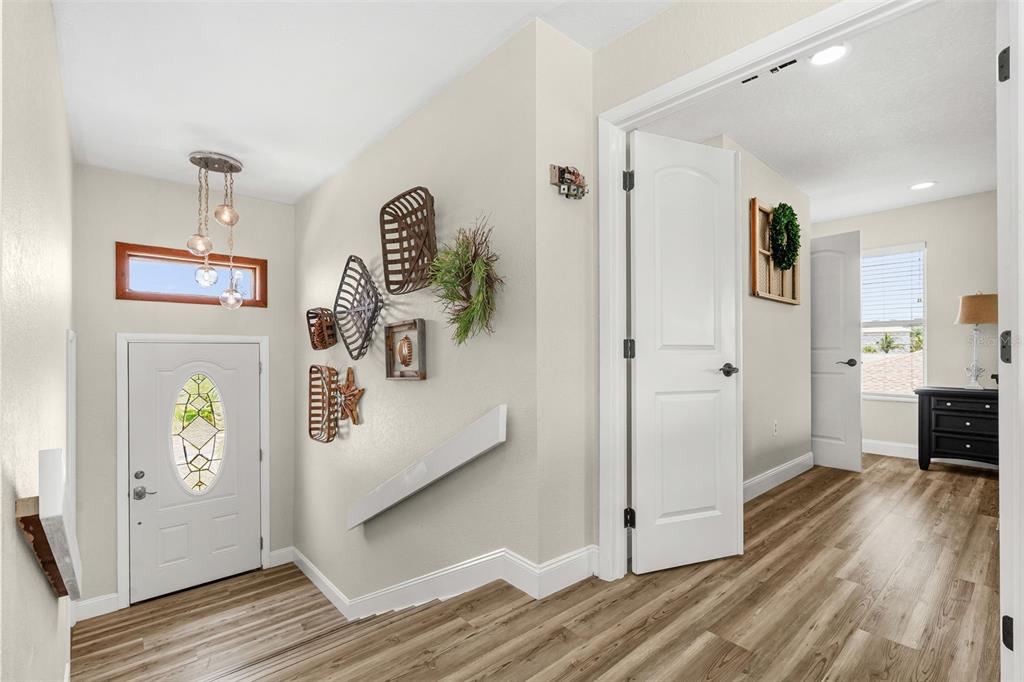 An entryway features wood-look flooring, a white front door, and a wall decorated with baskets — 5404 BAY STATE ROAD, PALMETTO, FL