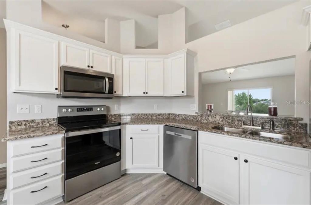 A kitchen with white cabinets, stainless steel appliances, and granite countertops — 202 HIGHLAND MEADOWS PLACE, DAVENPORT, FL