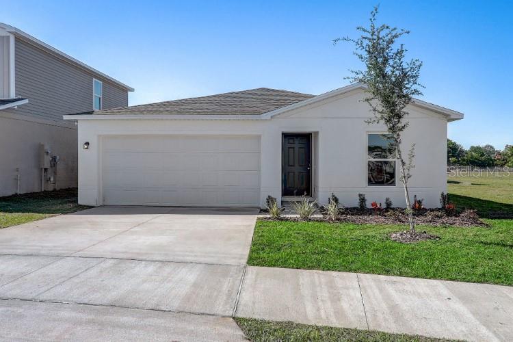 A single-story house with a white stucco exterior, a two-car garage, and a dark front door — 8305 WINTER GARDEN PARKWAY, FORT PIERCE, FL