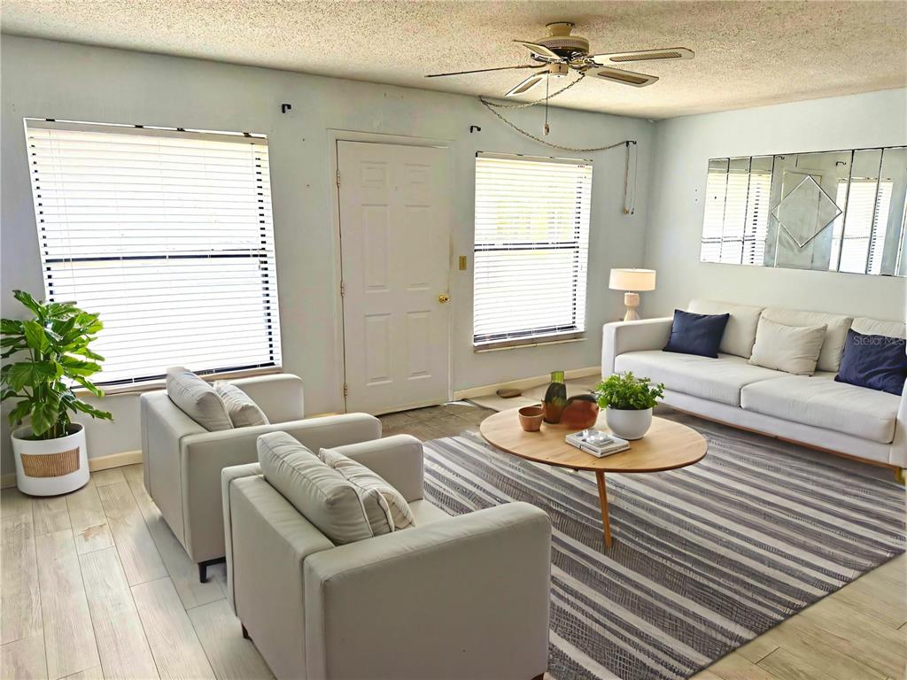 A living room features light wood flooring, a white sofa, two armchairs, and a round table — 112 LACOSTA LANE UNIT 116, DAYTONA BEACH, FL
