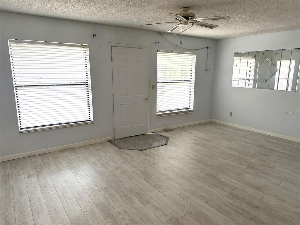 A living room features light wood-look flooring, a ceiling fan, and a front entry door — 112 LACOSTA LANE UNIT 116, DAYTONA BEACH, FL