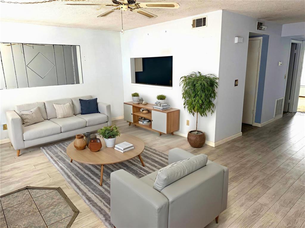 A living room features a gray sofa, a round coffee table, and a built-in television niche — 112 LACOSTA LANE UNIT 116, DAYTONA BEACH, FL