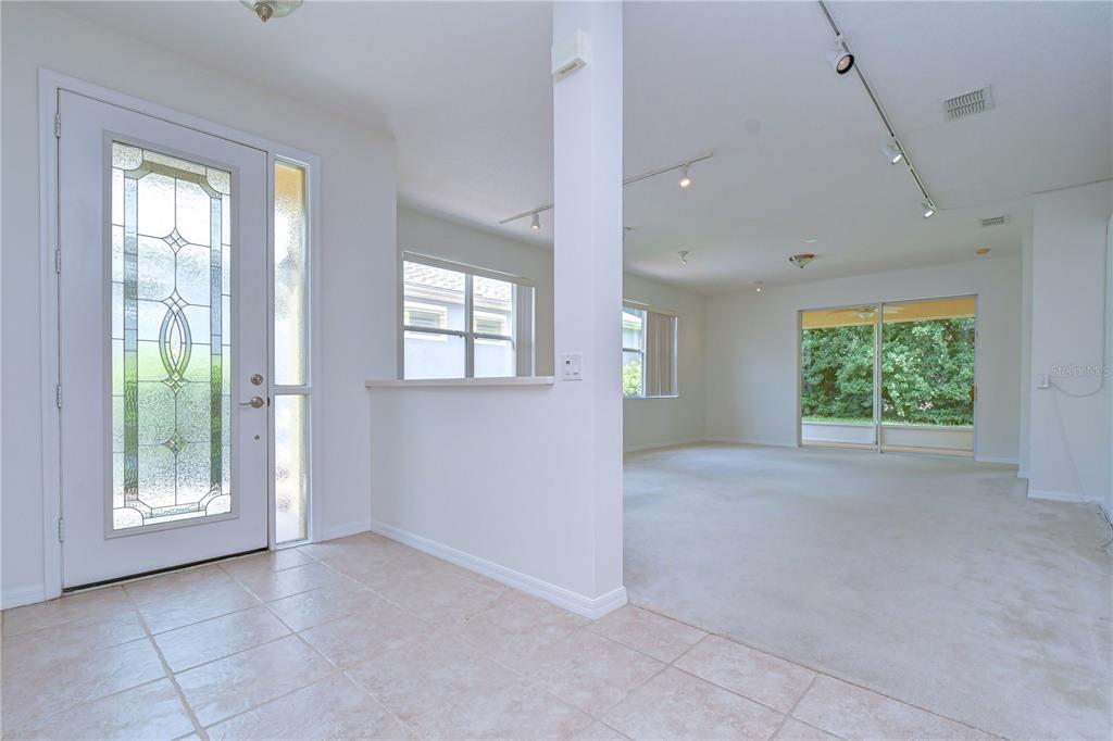 An entryway with tile flooring leads into a carpeted living area with sliding glass doors — 8049 SANGUINELLI ROAD, LAND O LAKES, FL
