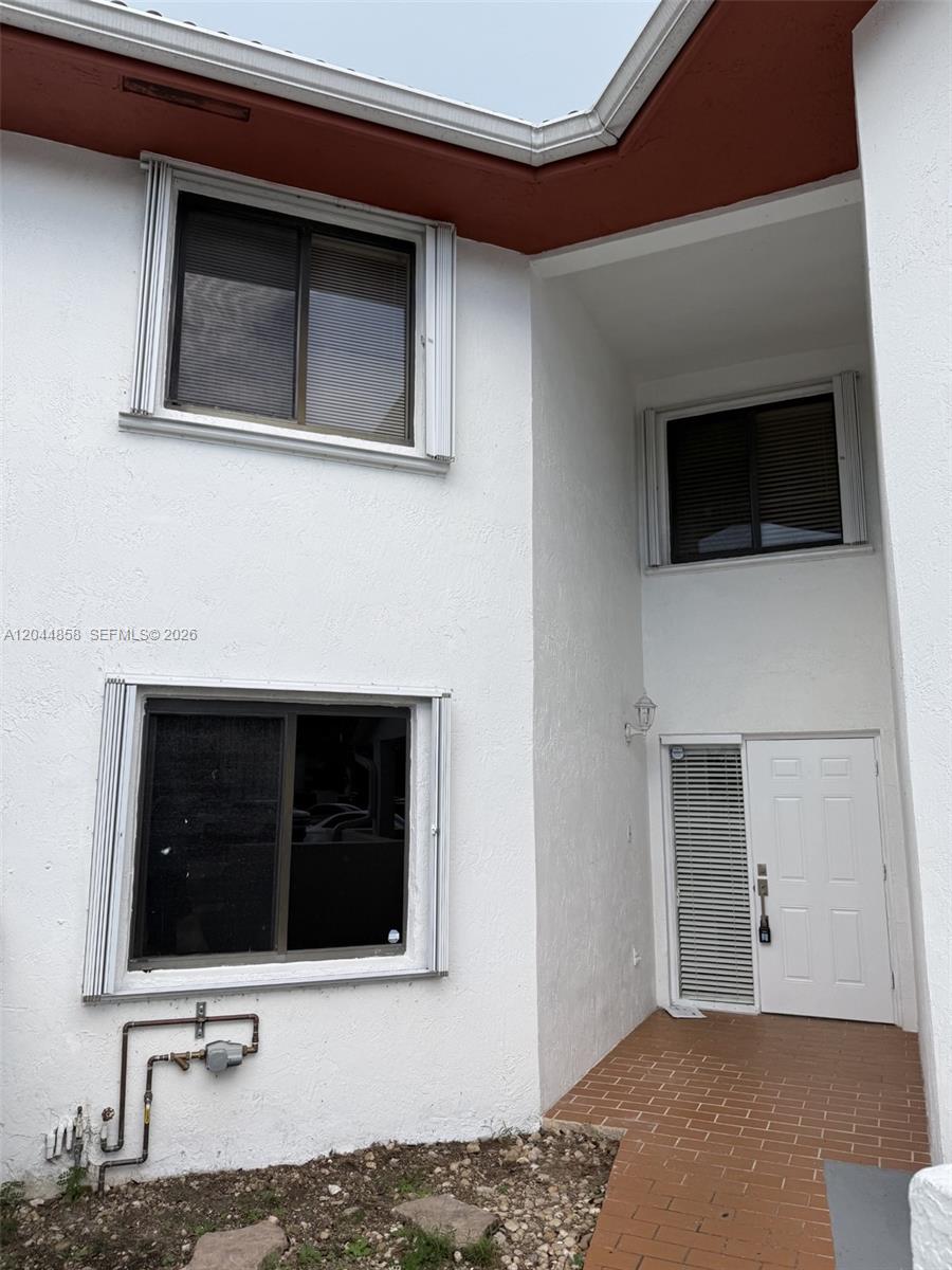 The exterior of a two-story white stucco building features a brick walkway and front door — 9686 SW 138th Ave # 9686, Miami FL 33186, MIAMI, FL