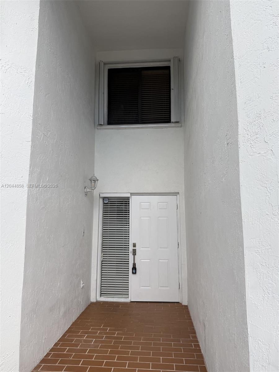 A white exterior entryway features a brick floor, a front door, and two windows — 9686 SW 138th Ave # 9686, Miami FL 33186, MIAMI, FL