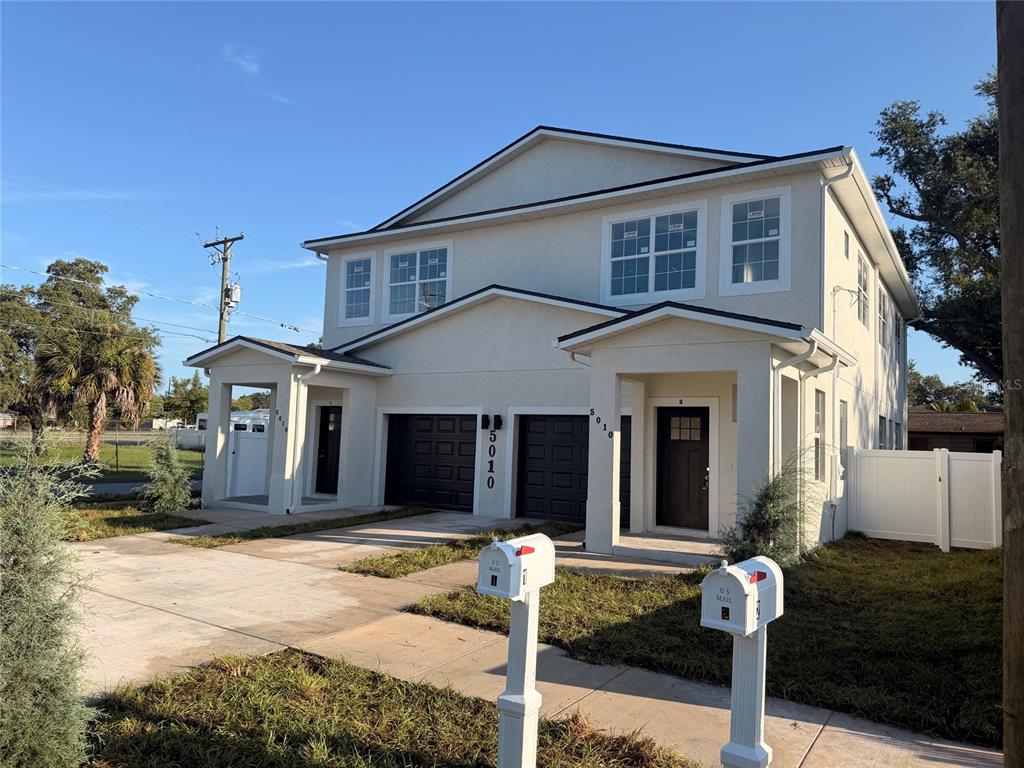 A two-story duplex with a light-colored exterior, two garages, and two mailboxes in front — 5010 E 32ND AVENUE UNIT 2, TAMPA, FL