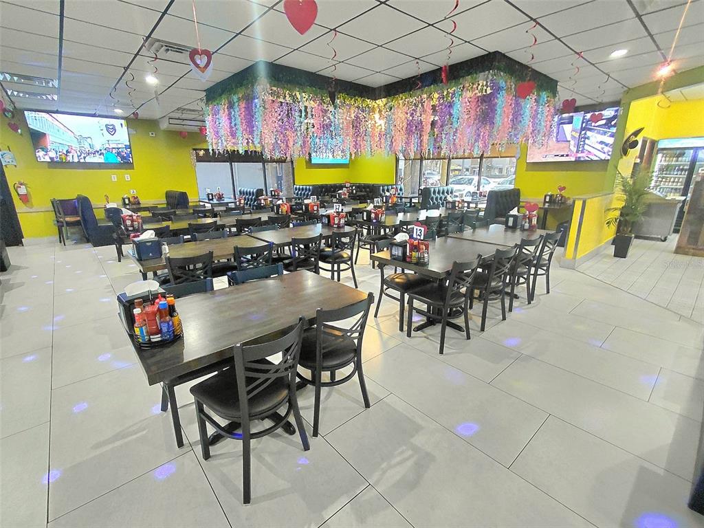 A restaurant dining room features tables, black chairs, and floral ceiling decorations — 909 W VINE STREET, KISSIMMEE, FL