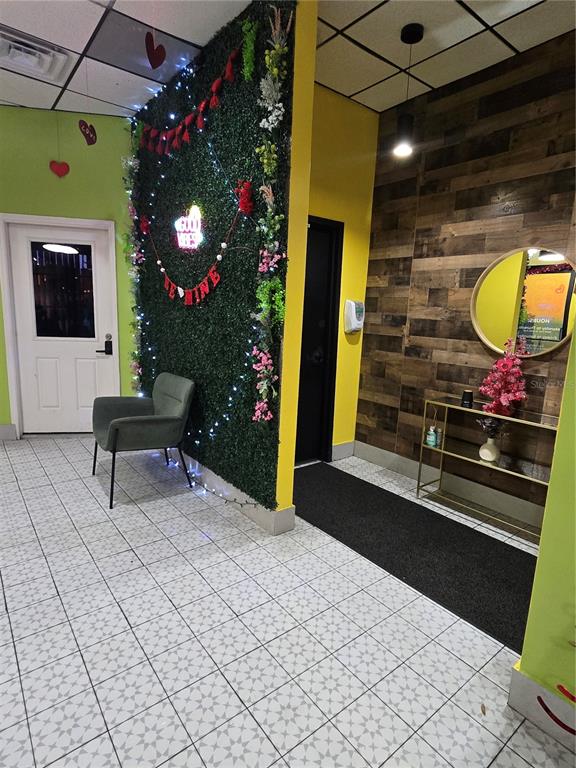 A room features a green wall with floral decor, a gray chair, and wood-paneled walls — 909 W VINE STREET, KISSIMMEE, FL