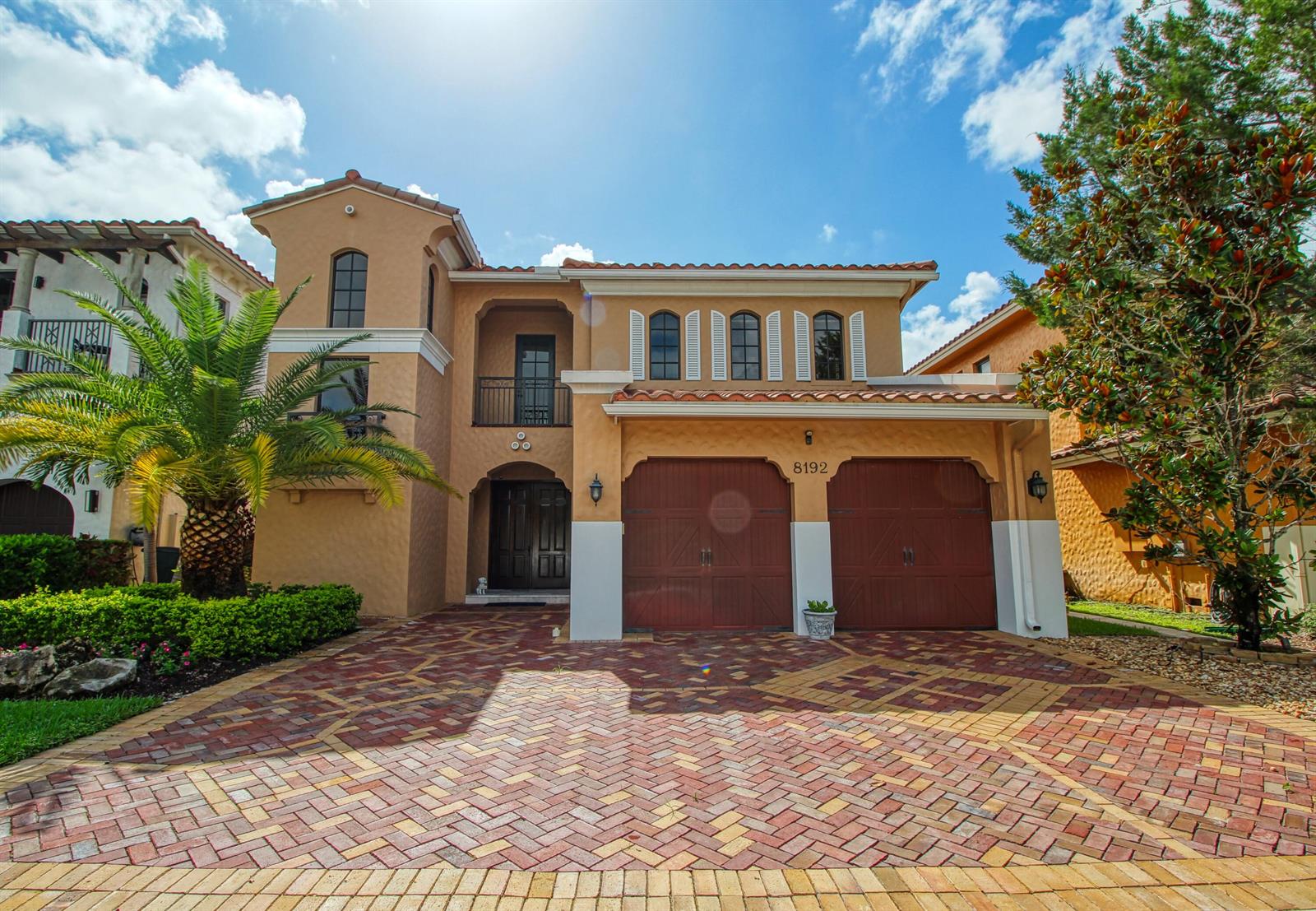 A two-story Mediterranean-style house features a brick paver driveway, a two-car garage, and a palm tree — 8192 Canopy Terrace, Parkland FL 33076, PARKLAND, FL
