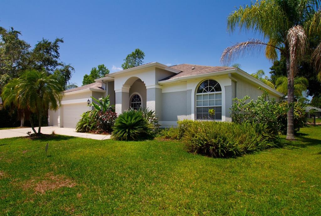 A single-story house with a white arched entryway, a two-car garage, and a landscaped lawn — 2456 APPALOOSA TRAIL, PALM HARBOR, FL