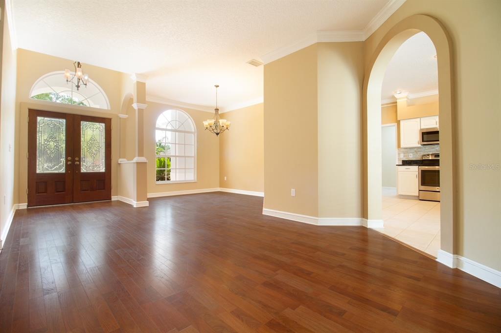A foyer and dining area with hardwood floors, arched doorways, and a view into the kitchen — 2456 APPALOOSA TRAIL, PALM HARBOR, FL