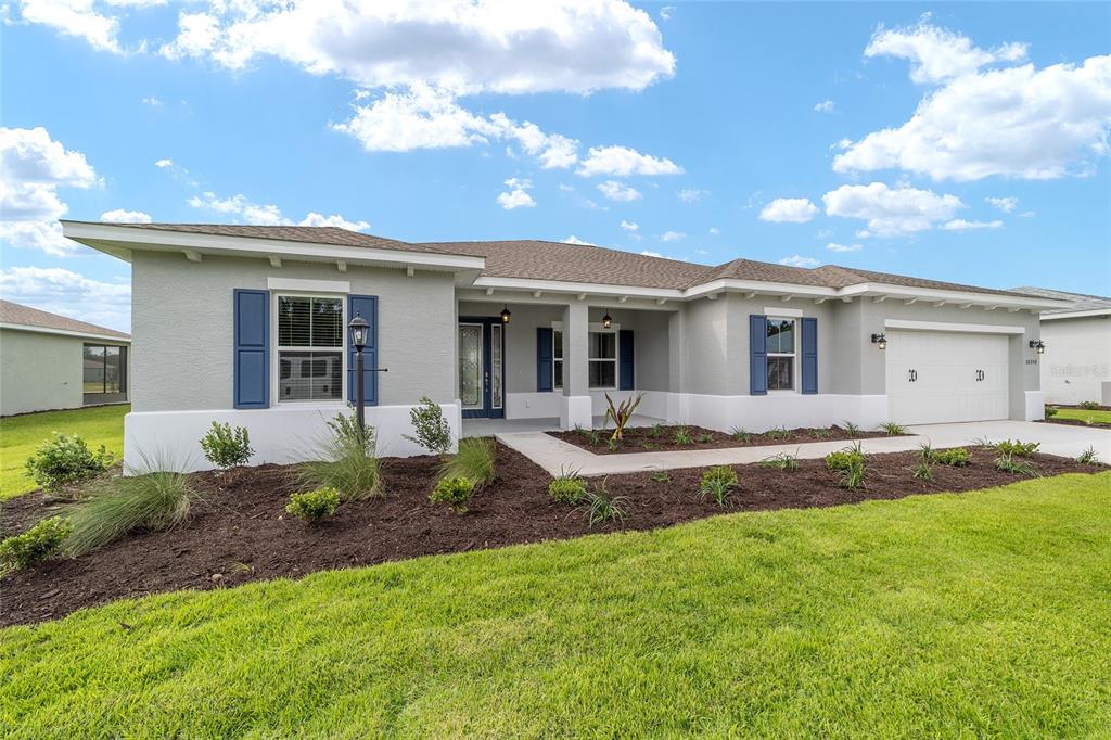 A single-story suburban house with a gray exterior, blue shutters, and a two-car garage — 10358 SW 105TH COURT, OCALA, FL