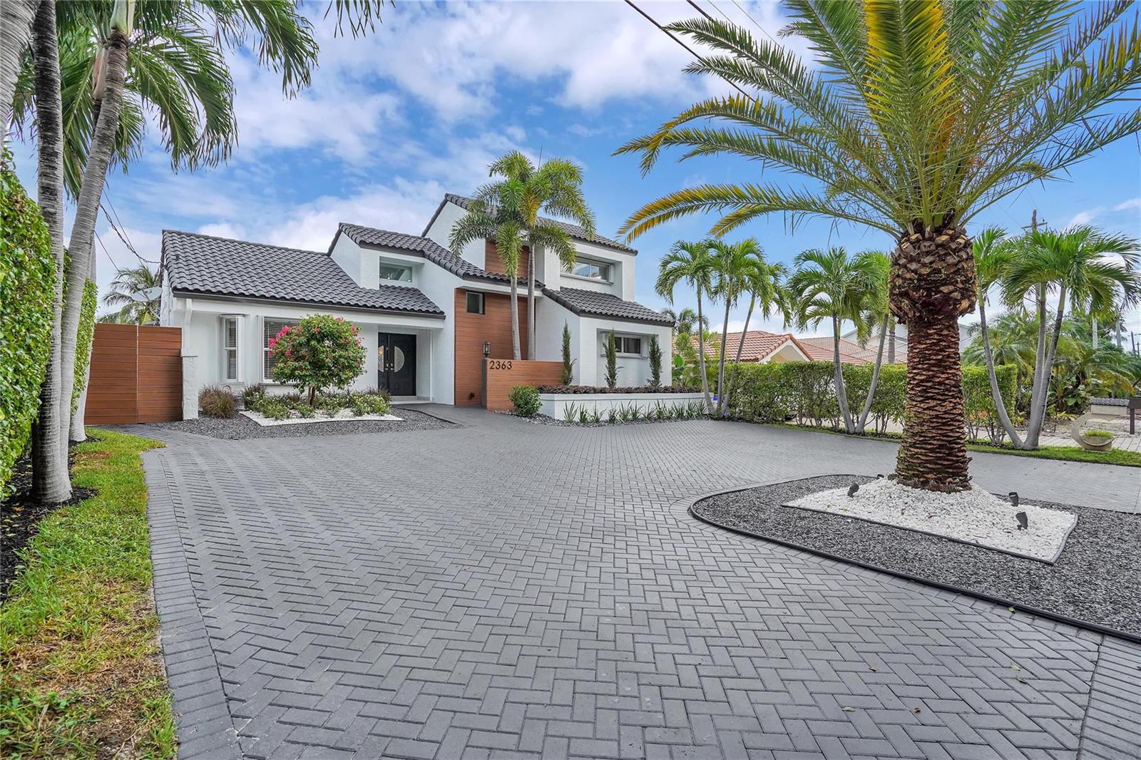A two-story house with a white exterior, wood accents, and a gray herringbone paver driveway — 2363 SE 15th Street, Pompano Beach FL 33062, POMPANO BEACH, FL