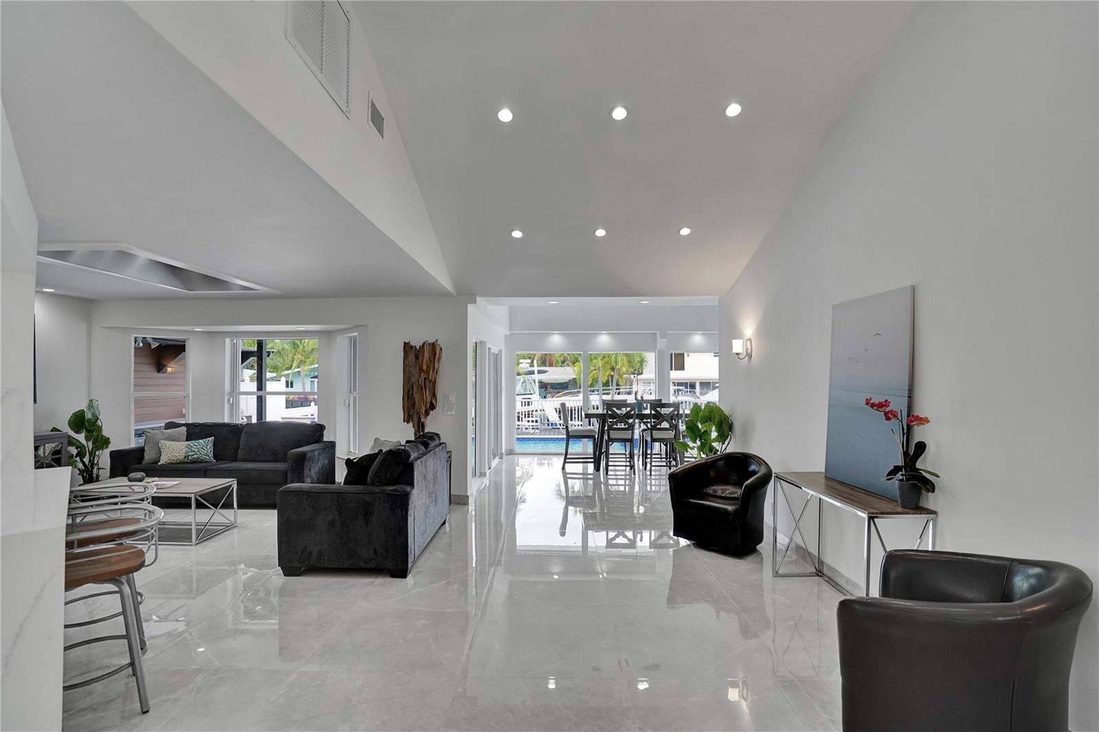 A bright, open-concept living and dining area features white tile floors and vaulted ceilings — 2363 SE 15th Street, Pompano Beach FL 33062, POMPANO BEACH, FL