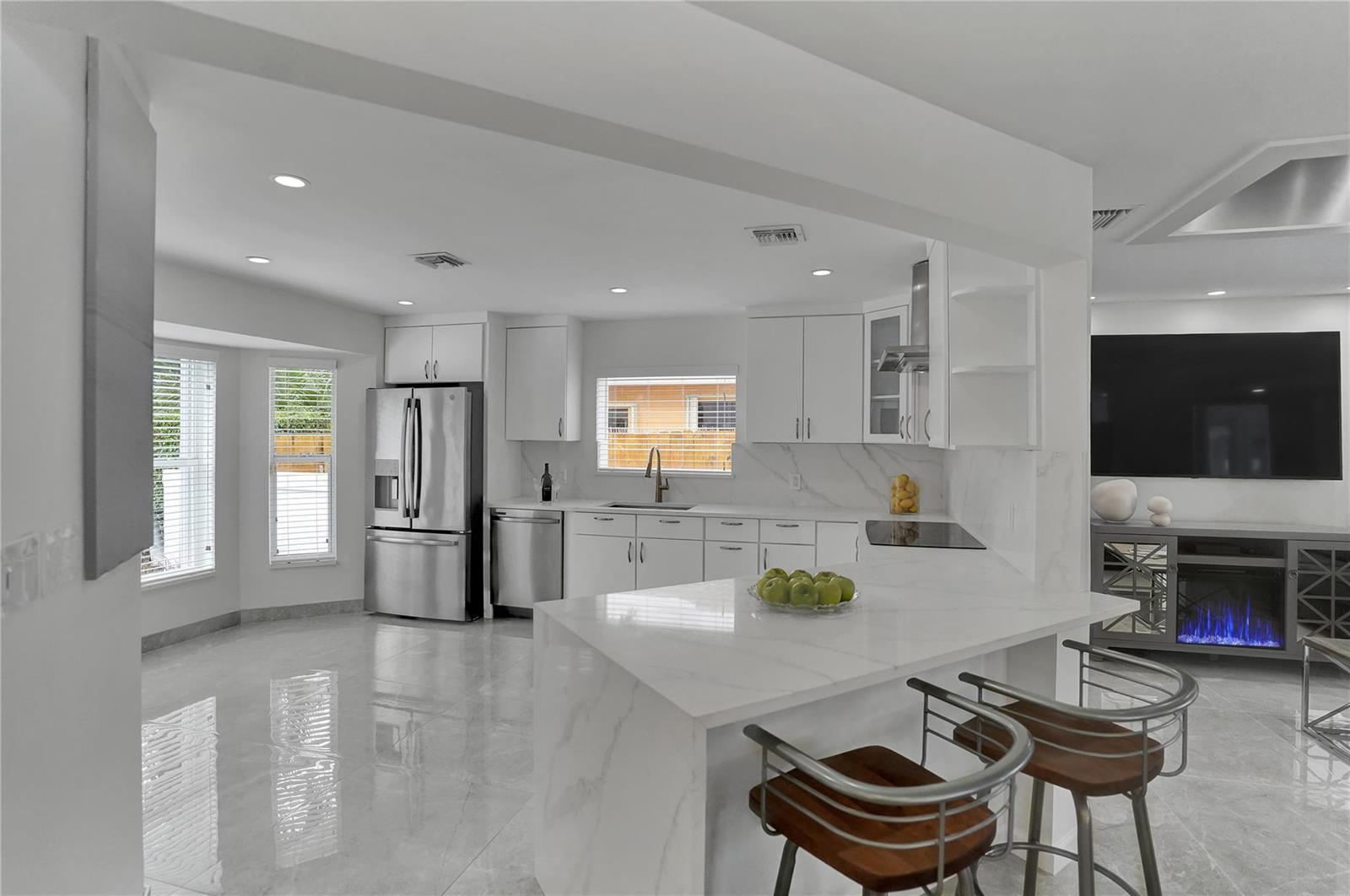 A modern kitchen features white cabinets, marble countertops, stainless steel appliances, and a breakfast bar — 2363 SE 15th Street, Pompano Beach FL 33062, POMPANO BEACH, FL