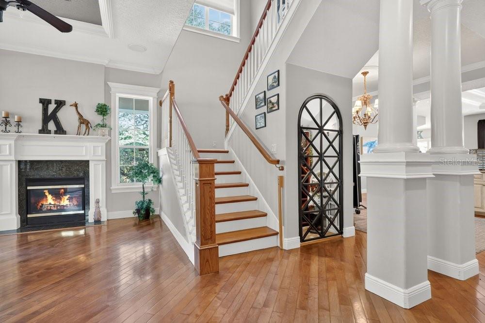 A foyer features hardwood floors, a fireplace, a staircase, and a decorative arched metal screen — 106 CALLAWAY COURT, DELAND, FL
