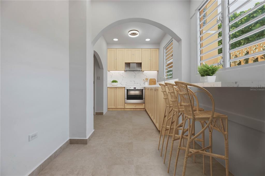 A galley kitchen features light wood cabinets, a marble-look backsplash, and a breakfast bar — 16 PACIFIC PLACE STREET, SAN JUAN, PR