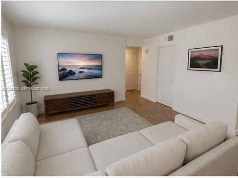 A living room features a white sectional sofa, a wall-mounted television, and a wooden media console — 7880 SW 55th Ave # A, Miami FL 33143, MIAMI, FL