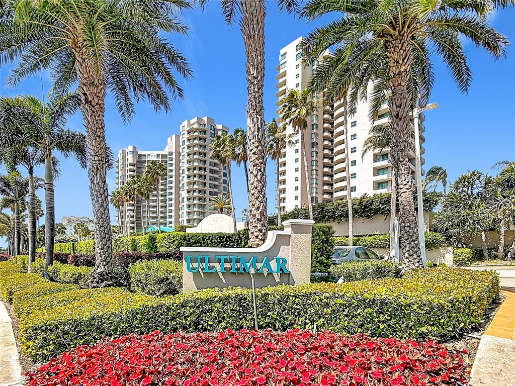 The exterior of the Ultimar residential complex features tall palm trees and a landscaped entrance — 1540 GULF BOULEVARD UNIT 304, CLEARWATER BEACH, FL