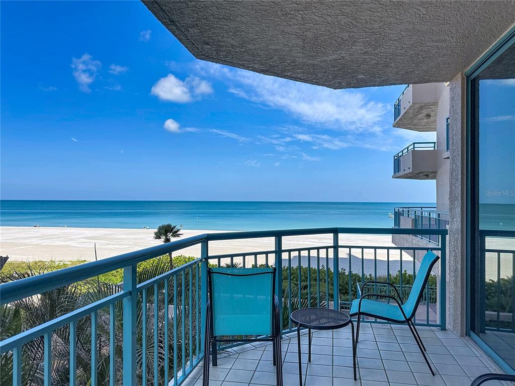 A balcony with two chairs and a small table overlooks a beach and ocean — 1540 GULF BOULEVARD UNIT 304, CLEARWATER BEACH, FL
