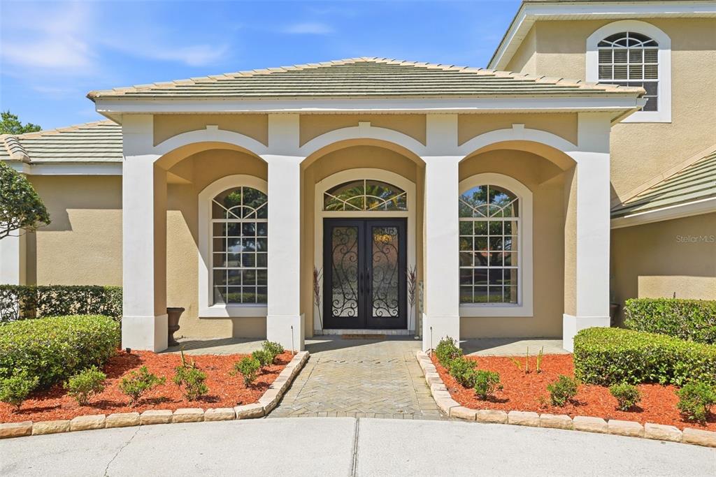 A two-story house with a circular driveway, a central palm tree, and evening exterior lighting — 9119 BALMORAL MEWS SQ, WINDERMERE, FL