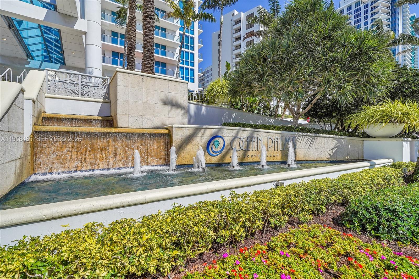 A tiered stone fountain with water jets sits in front of a modern residential building — 3101 S OCEAN # 1802, Hollywood FL 33019, HOLLYWOOD, FL