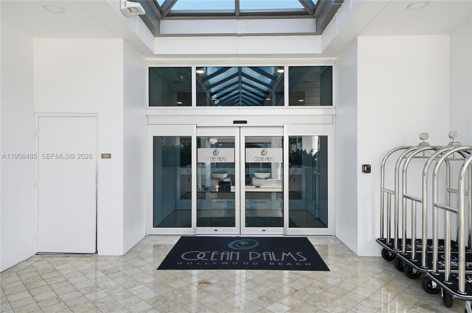 The entrance to Ocean Palms features glass sliding doors, a skylight, and luggage carts — 3101 S OCEAN # 1802, Hollywood FL 33019, HOLLYWOOD, FL