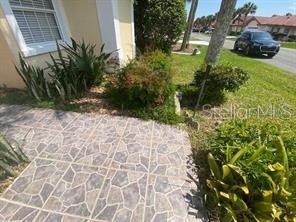 A stone-patterned walkway leads to the side of a house with landscaping and a car — 30 SAN RAFAEL COURT, PALM COAST, FL