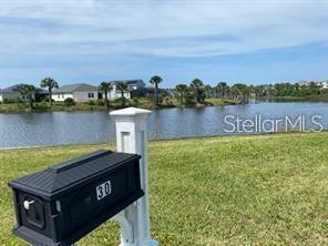 A black mailbox stands in the foreground of a grassy lawn overlooking a pond and houses — 30 SAN RAFAEL COURT, PALM COAST, FL