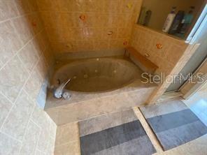 A tiled bathroom features a built-in jetted soaking tub and two gray bath mats — 30 SAN RAFAEL COURT, PALM COAST, FL