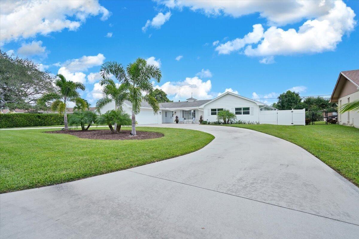 A white single-story house with a curved concrete driveway and palm trees on a lawn — 76 W Fairview W, Tequesta FL 33469, TEQUESTA, FL