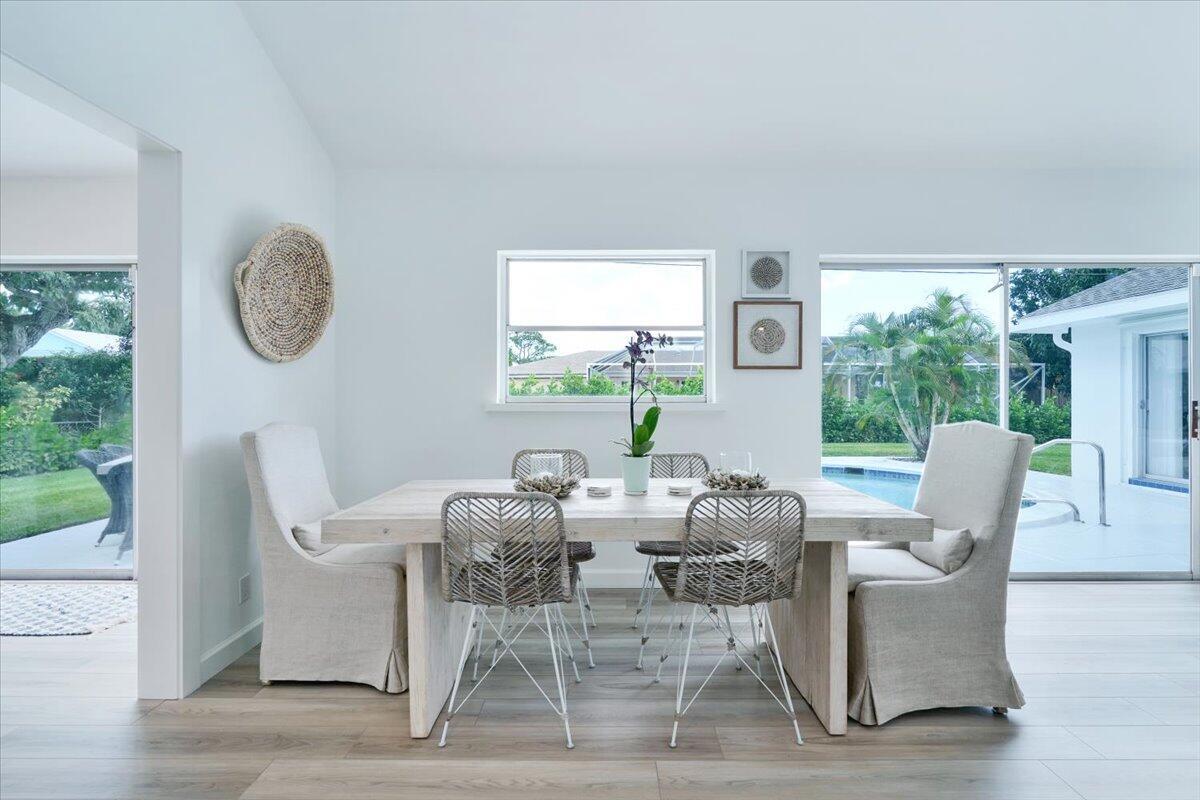 A dining room features a light wood table, upholstered chairs, and views of a pool — 76 W Fairview W, Tequesta FL 33469, TEQUESTA, FL