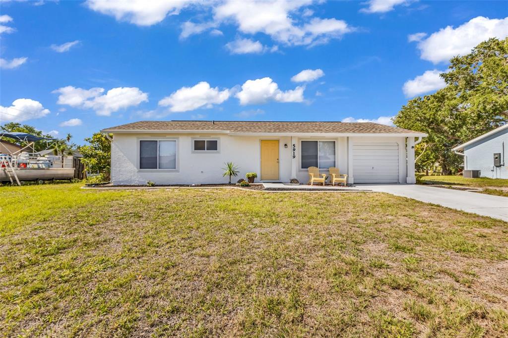 A single-story white house with a yellow front door, a garage, and a front lawn — 5919 HOBHILL AVENUE, NORTH PORT, FL