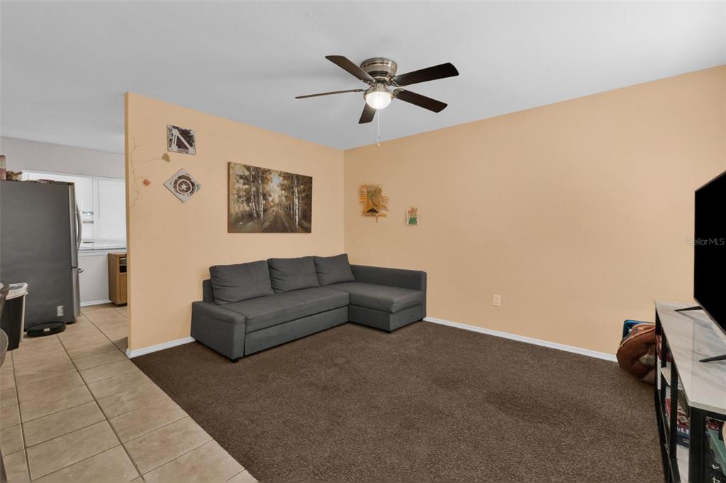 A living room features a gray sectional sofa, brown carpet, and a ceiling fan — 5919 HOBHILL AVENUE, NORTH PORT, FL